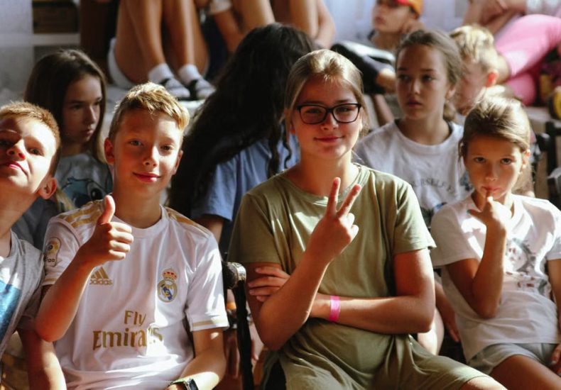 Cheerful group of children sitting together at an indoor event, showcasing friendships and diversity.